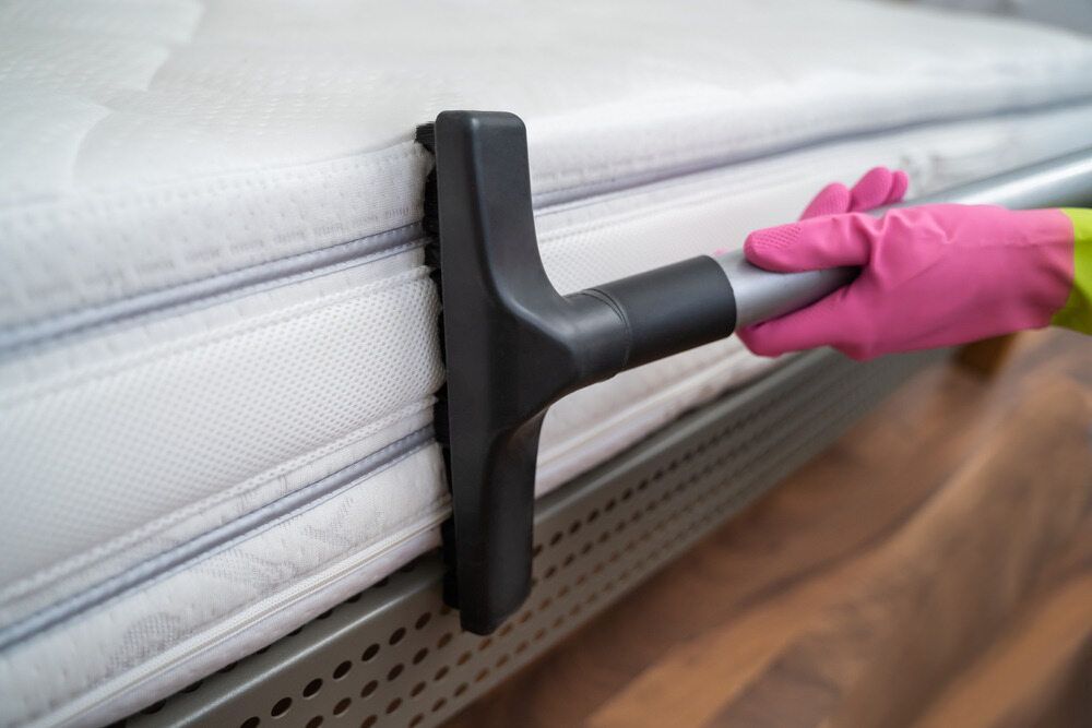Pink-Gloved Hand Vacuuming a White Mattress — Broadbeach Carpet Cleaning In Broadbeach, QLD