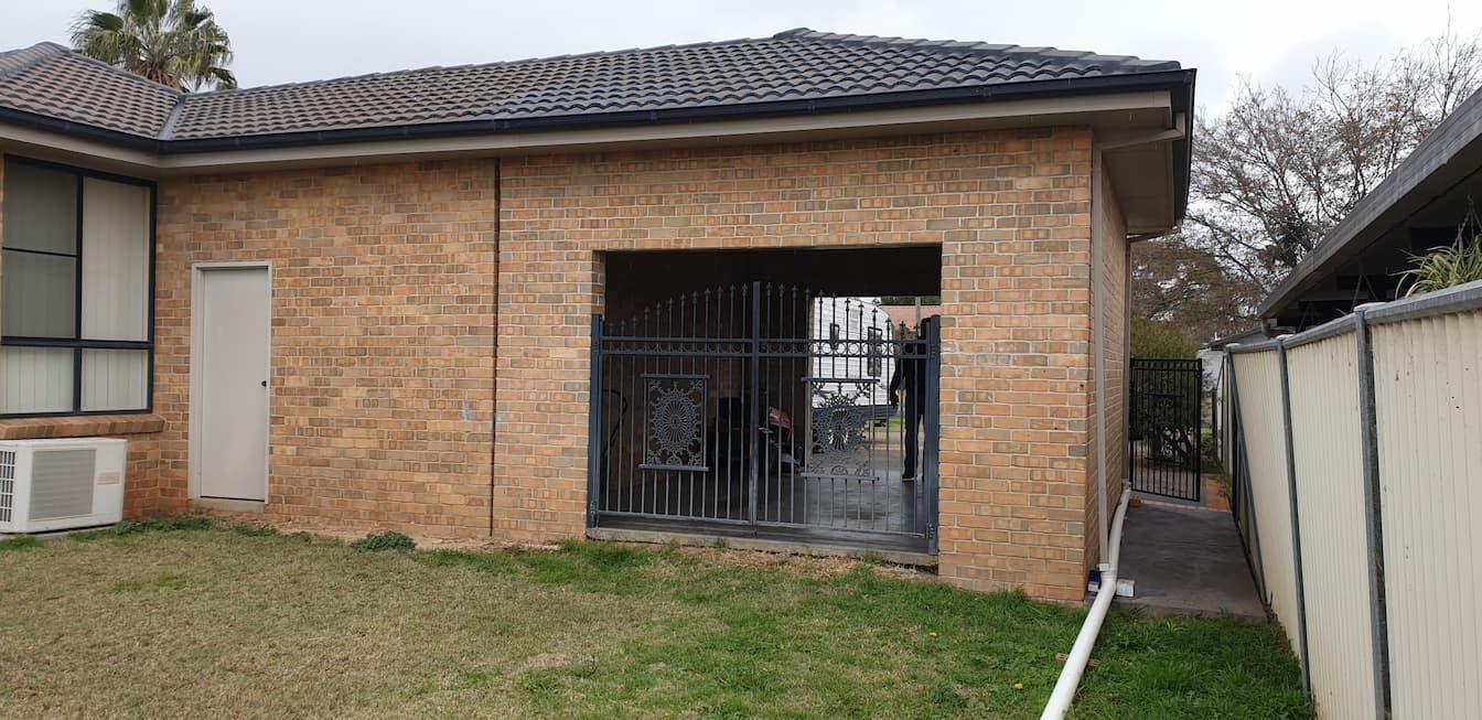 A Brick House with A Garage and A Fence in The Backyard — Edwards & Froud Building Services Pty Ltd in Tamworth, NSW
