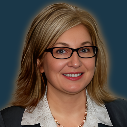 A woman wearing glasses and a pearl necklace smiles for the camera