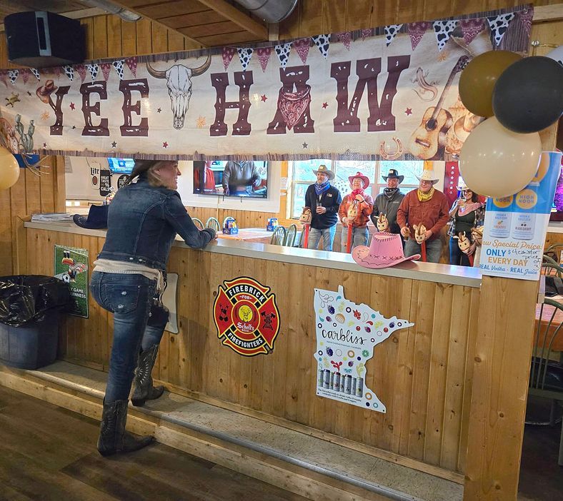Yee-haw booth with wooden counter, balloons, and staff serving drinks at a fair or festival