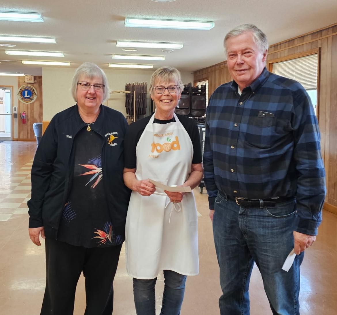 Three people standing together in a bright hallway, smiling at the camera.