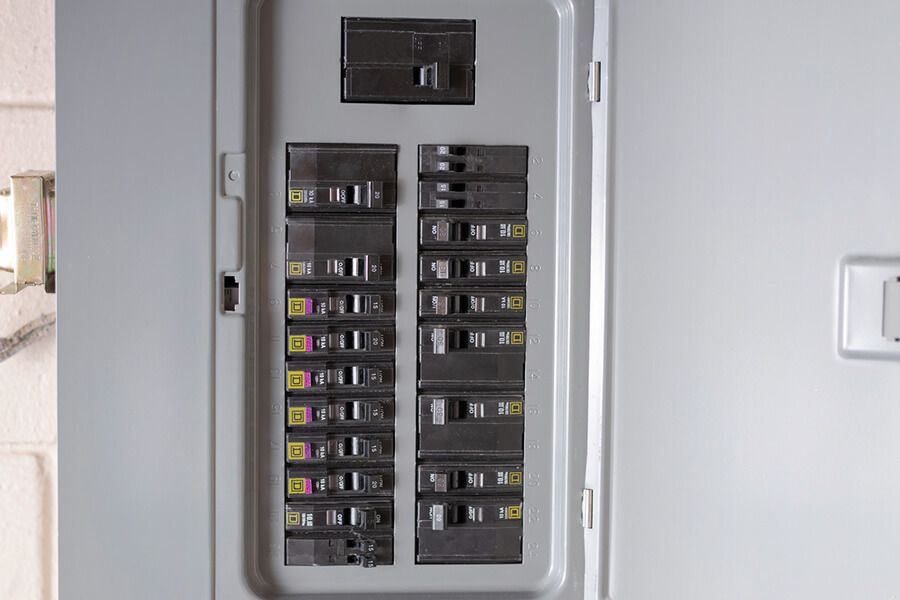 Open electrical breaker panel with multiple circuit switches in a wall recess