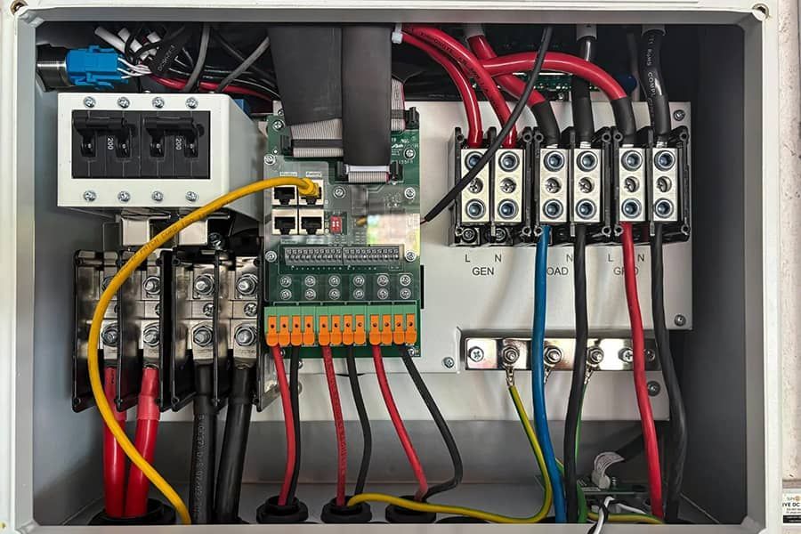 Open electrical control panel with circuit breakers, relays, terminal blocks, and colorful wiring.