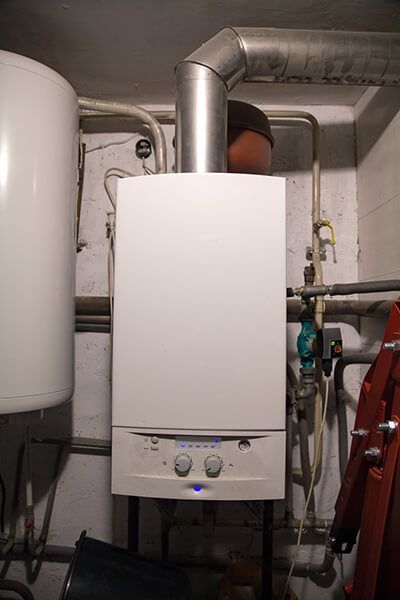 Wall-mounted white boiler with metal vent pipes in a utility room