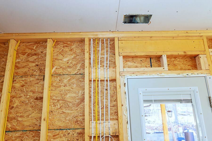 Interior wall framing with exposed insulation and electrical wiring around a doorway