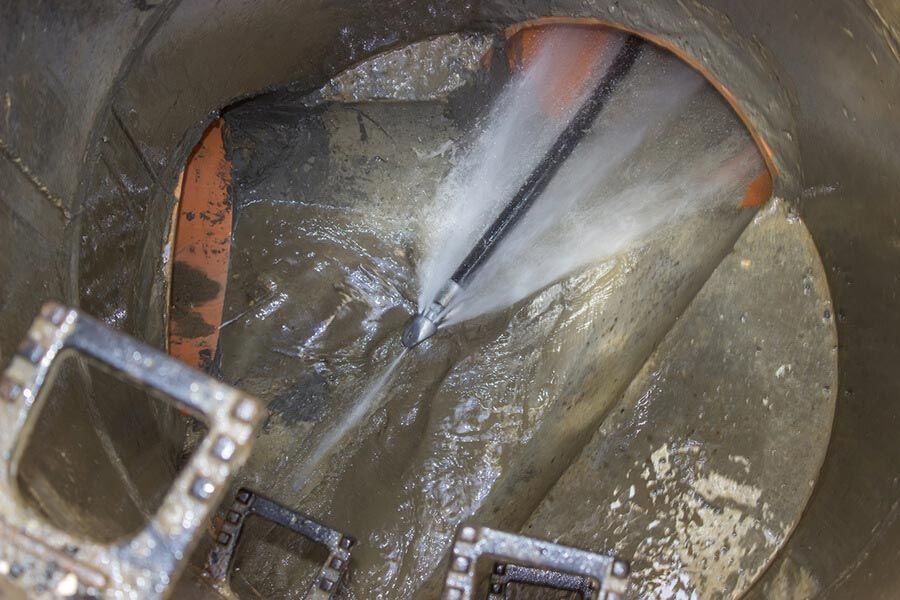 Inside a metal pipe, a blurred object shines against a wet, reflective interior.