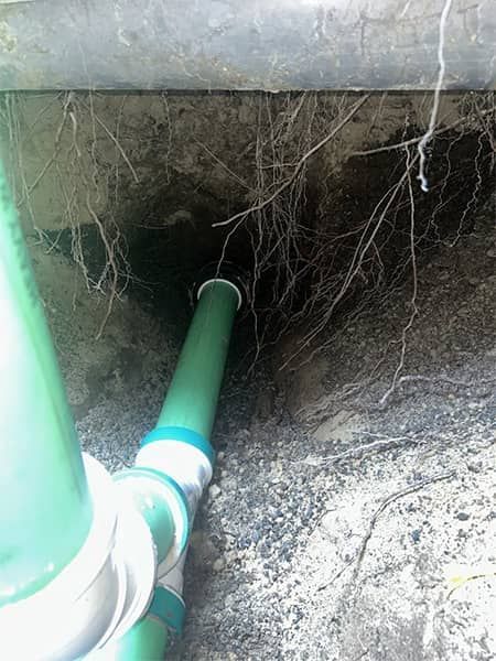 Green PVC pipes running into a dark underground hole