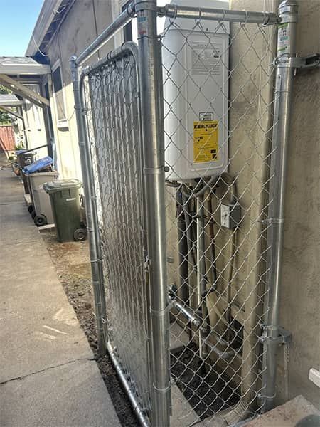 Outdoor utility equipment in a fenced enclosure beside a building