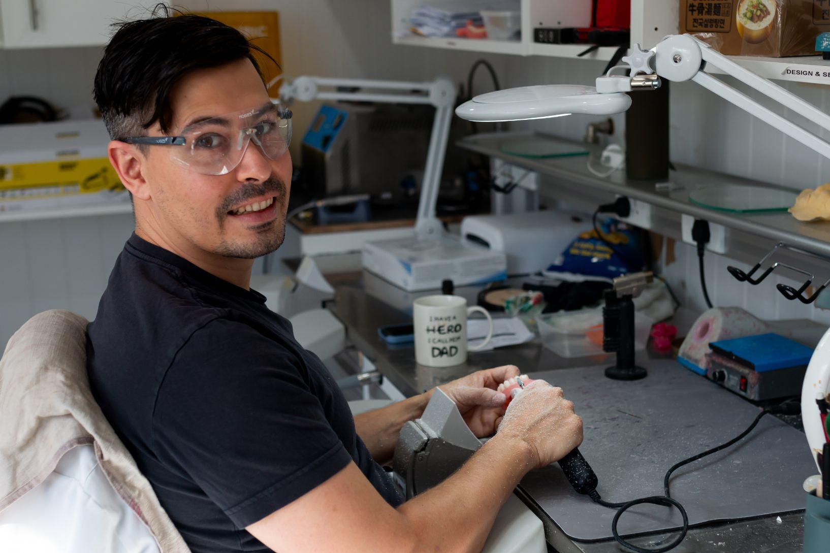 Man in Glasses Working at a Desk With Tools — Dentures Direct Ballina In Ballina, NSW