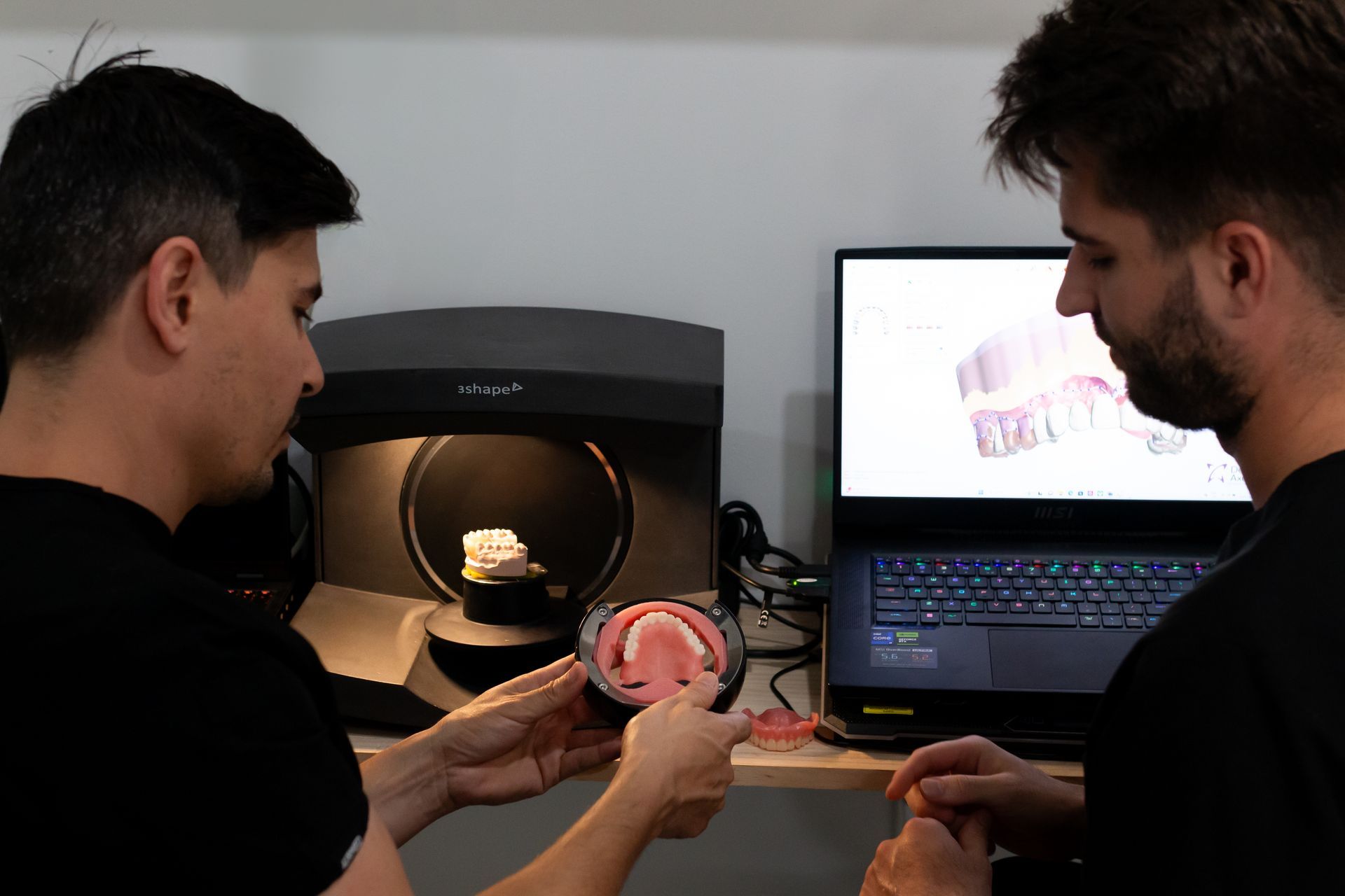 Two people examining a dental model. One holds the model, the other looks at a computer showing a teeth scan— Dentures Direct Ballina In Ballina, NSW