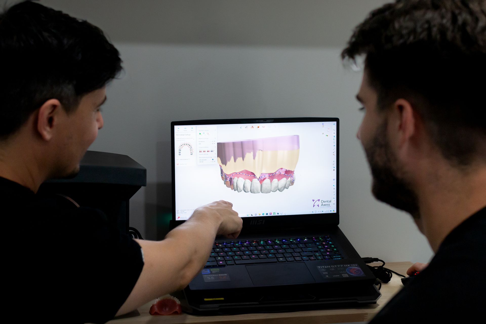 Two people looking at a laptop showing a 3D dental scan; one points at the screen.— Dentures Direct Ballina In Ballina, NSW