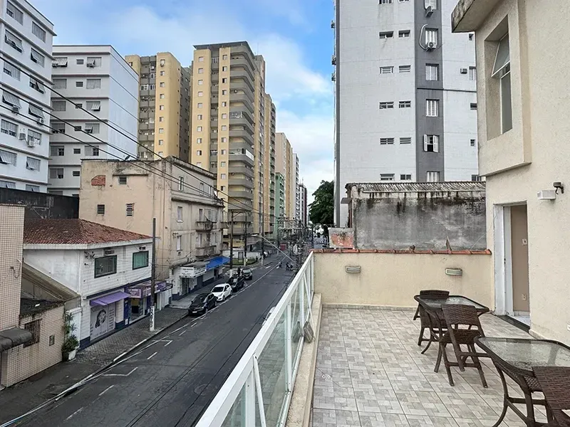 Uma varanda com mobiliário de exterior oferece vista para uma rua da cidade ladeada por altos edifícios residenciais.