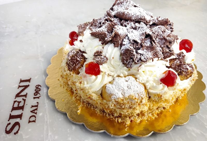 Una torta con ciliegie e zucchero a velo è appoggiata su un cartello steni dal 1909