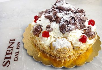 Una torta con ciliegie e zucchero a velo è appoggiata su un cartello steni dal 1909