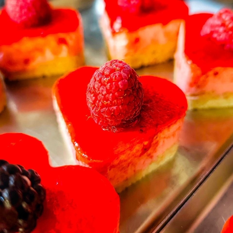 Un dolce a forma di cuore con un lampone sopra.