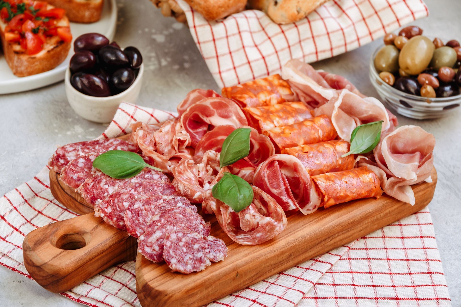 Un tagliere di legno sul quale sono disposti vari tipi di carne e olive.
