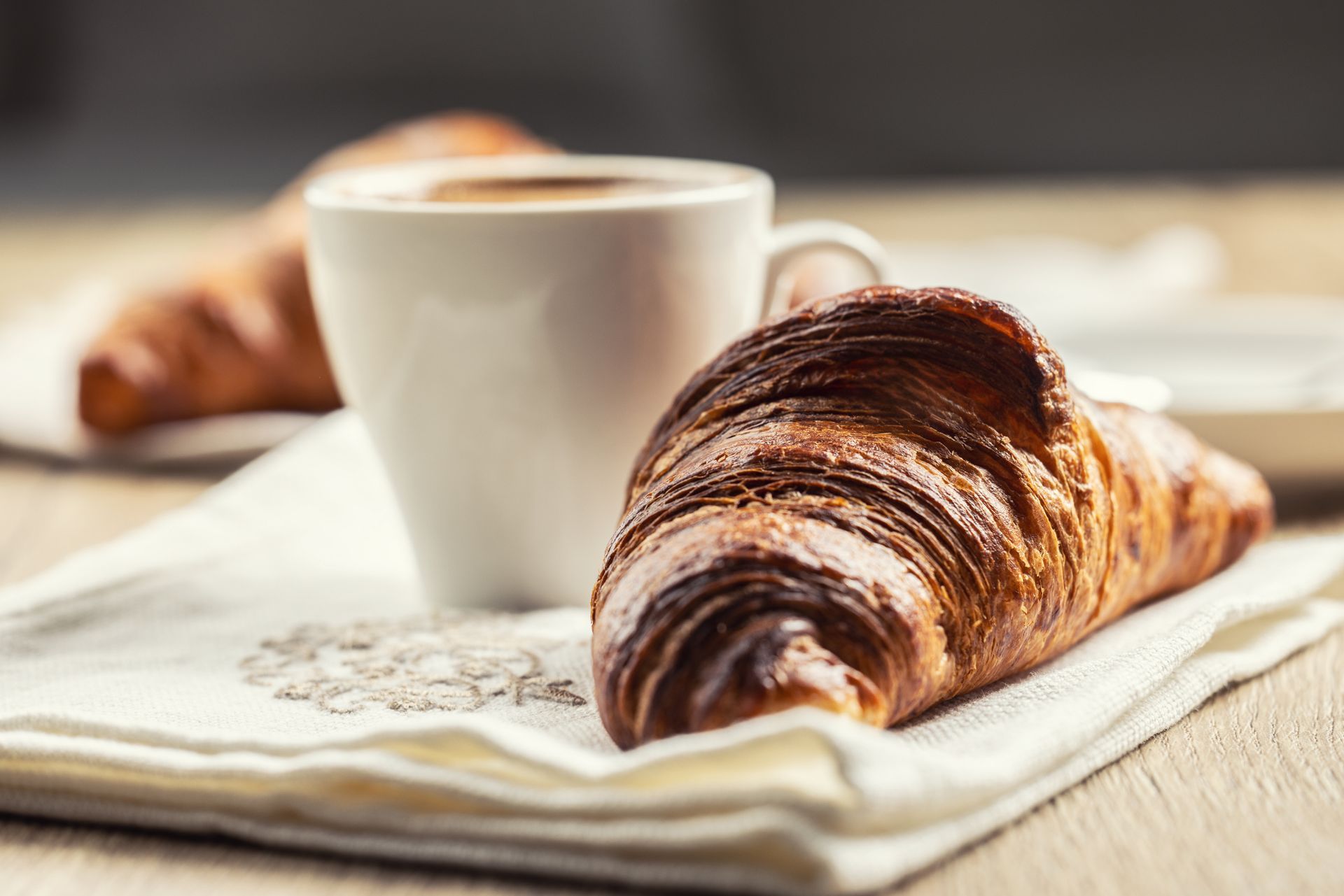 Un croissant e una tazza di caffè su un tovagliolo su un tavolo.