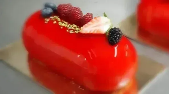Un primo piano di una torta rossa con bacche sopra.