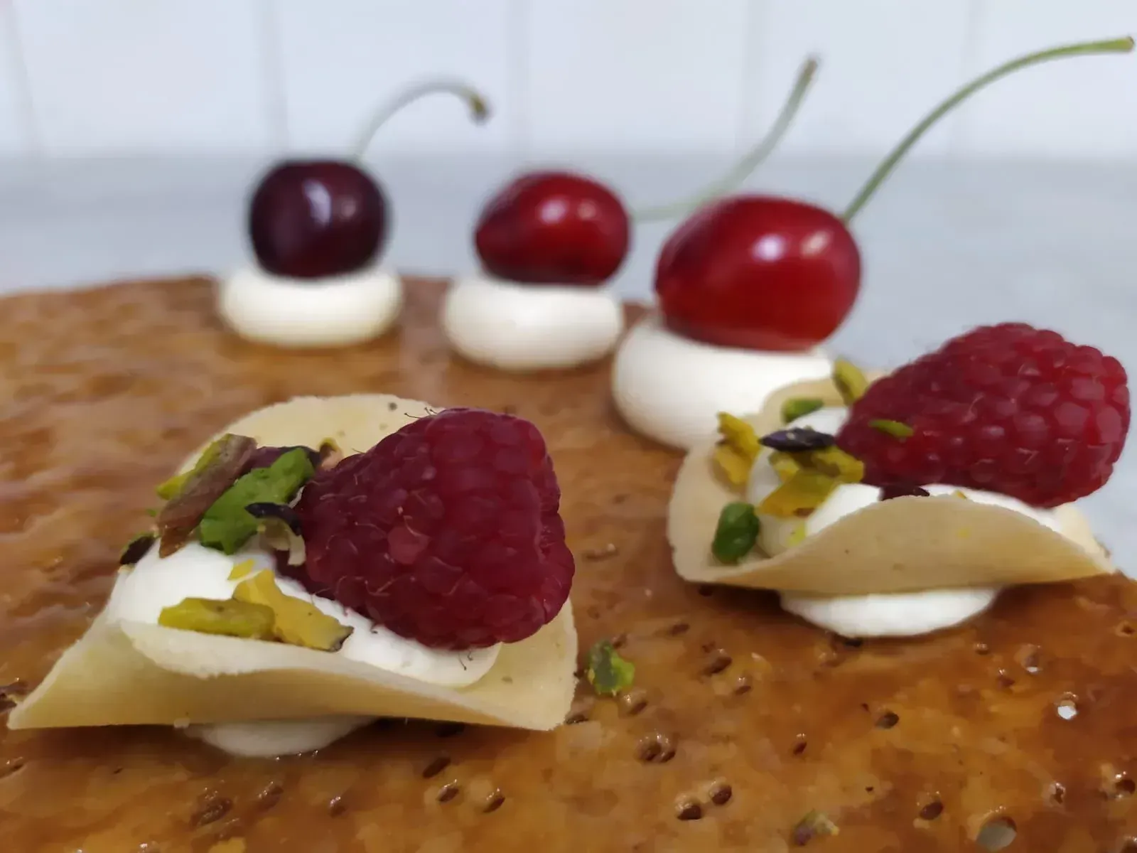 Un primo piano di un dessert con lamponi e ciliegie sopra