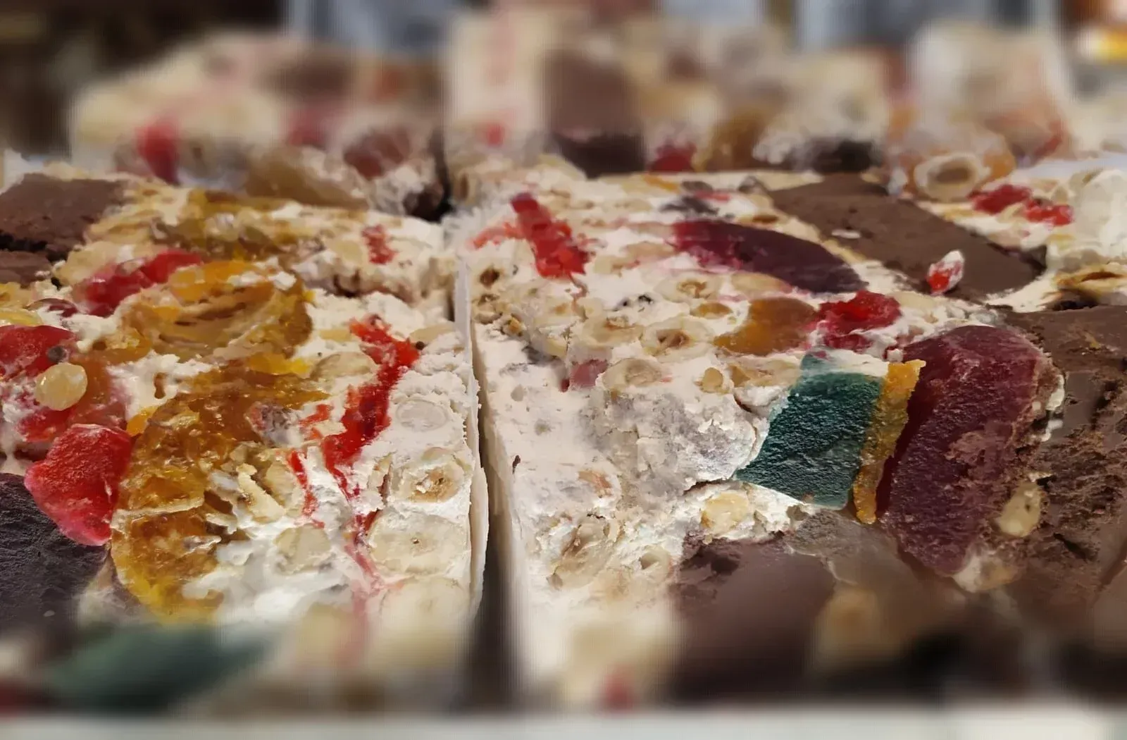 Un primo piano di una fetta di torta con noci e frutta sopra.