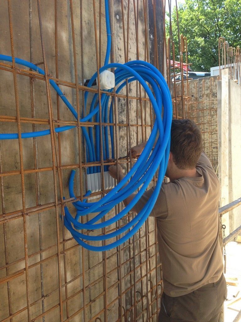 Un homme installe des tuyaux bleus sur un mur.