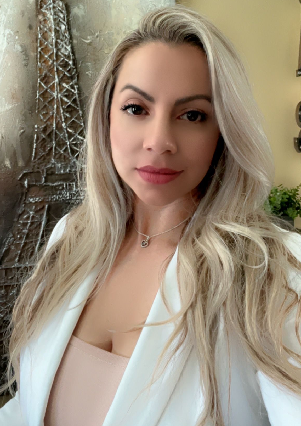 A woman is sitting at a desk with a laptop and a vase of flowers.