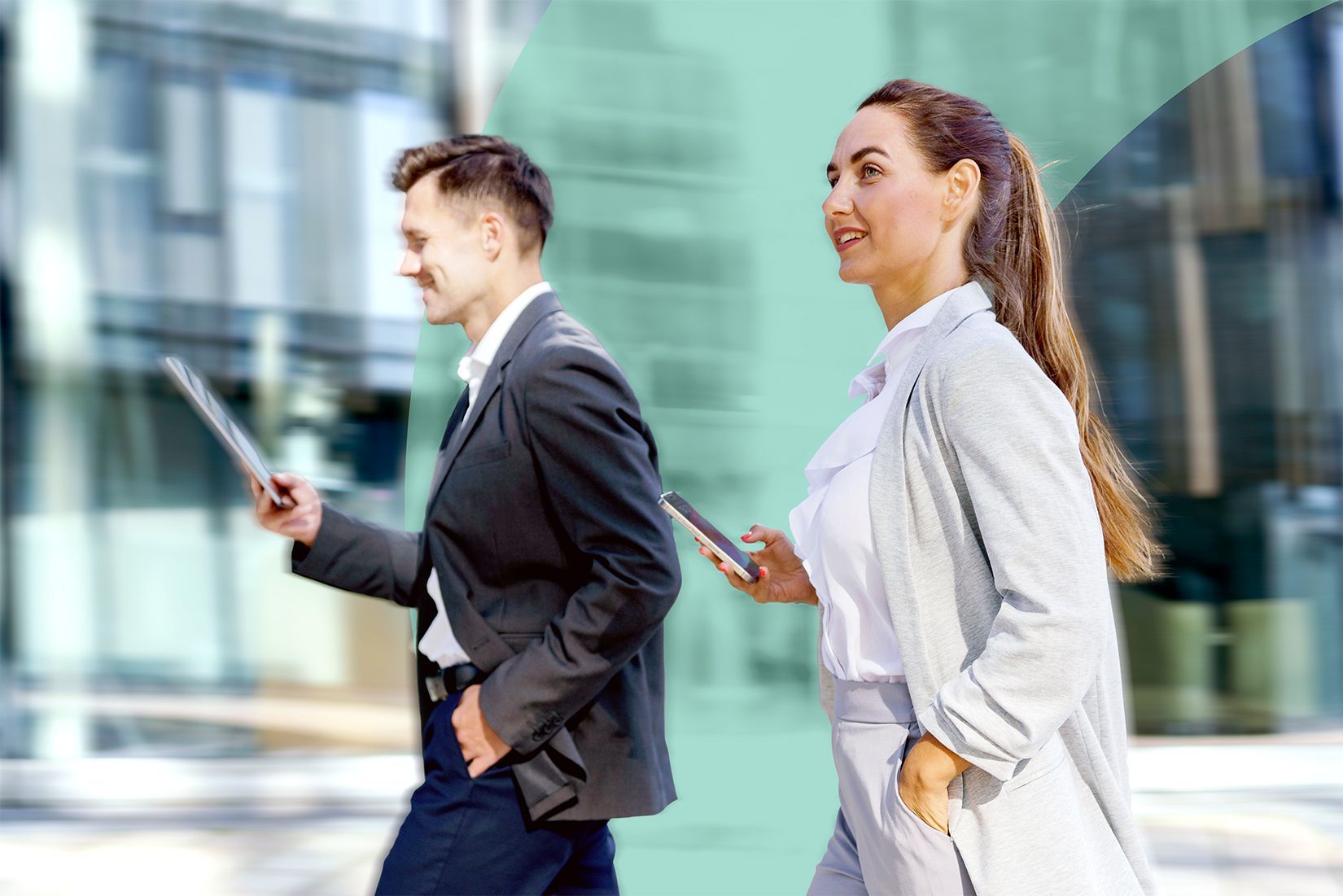 Two finance professionals walking quickly and confidently past a glass office building.