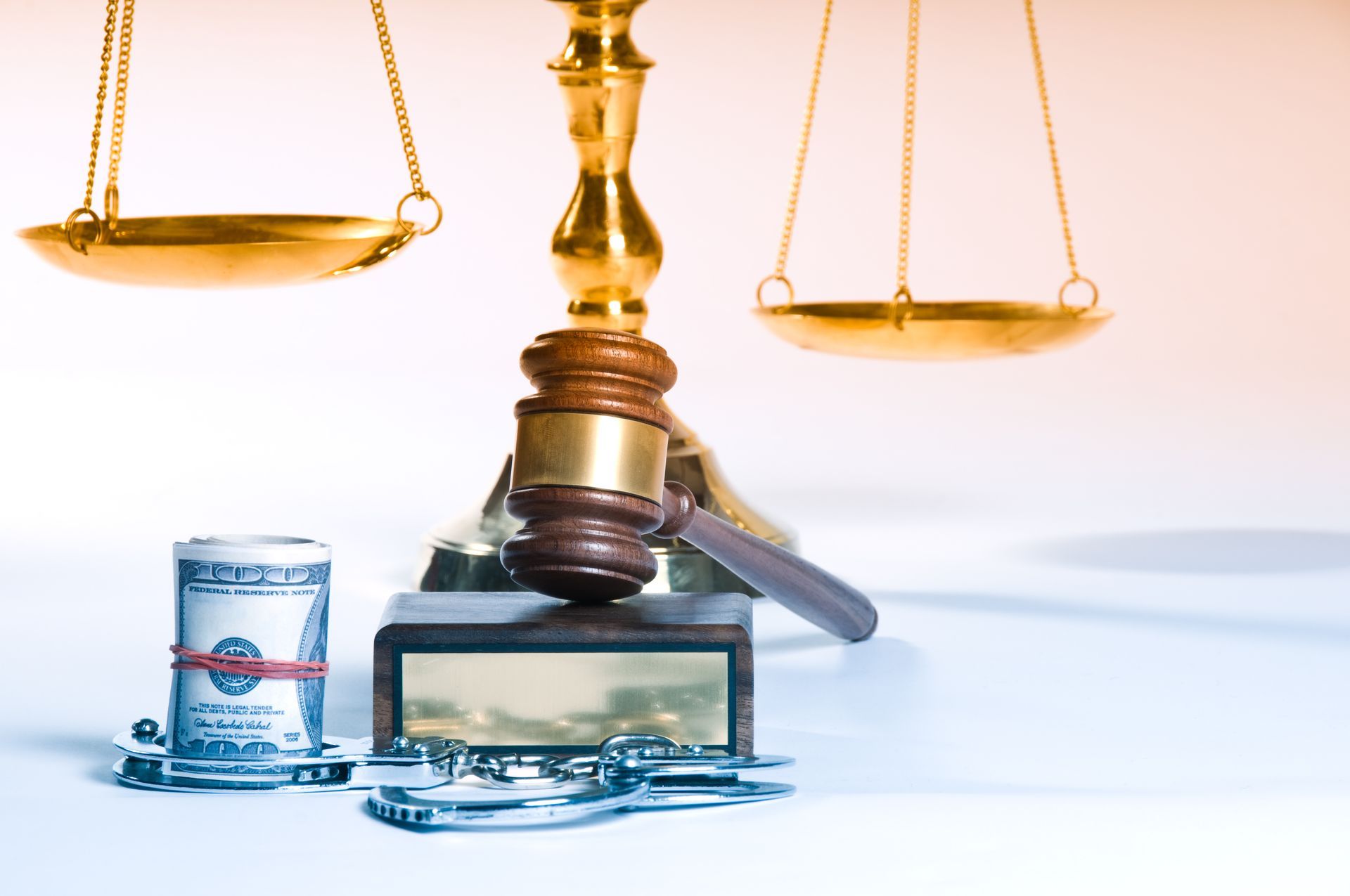 A judge 's gavel next to a stack of money and handcuffs