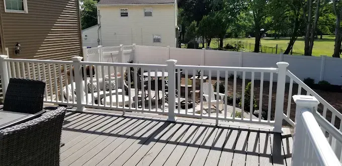 A deck with a white railing and a table and chairs on it.