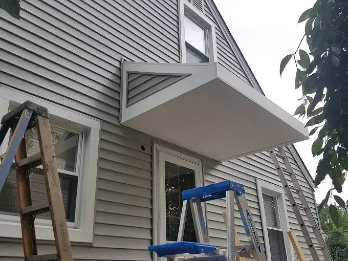 A ladder is sitting on the side of a house next to a window.
