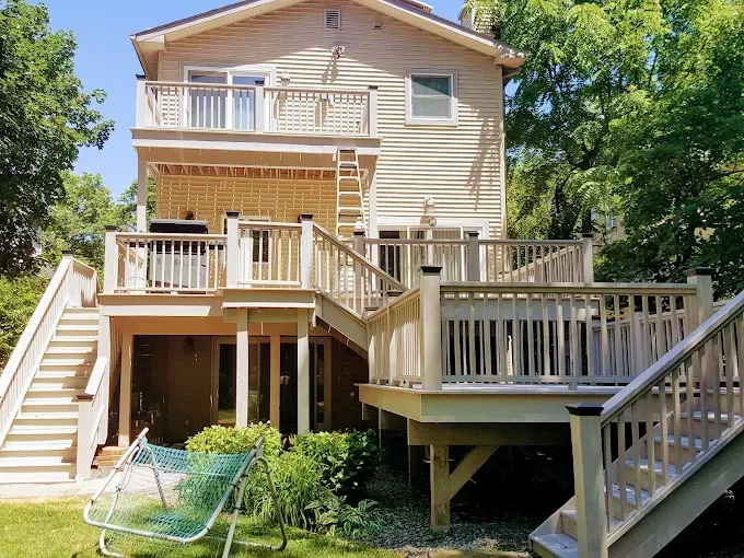 The back of a house with a large deck and stairs.