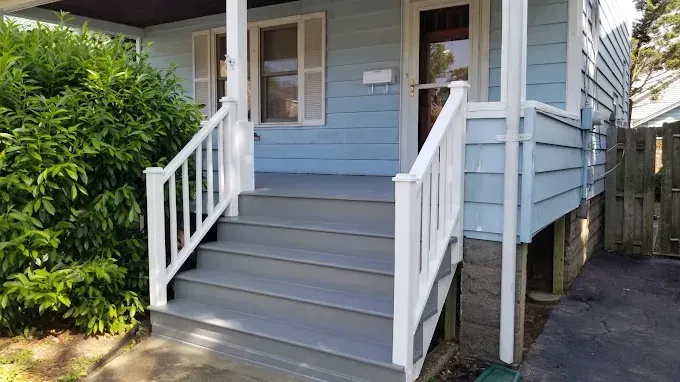 A blue house with white stairs and a white railing.