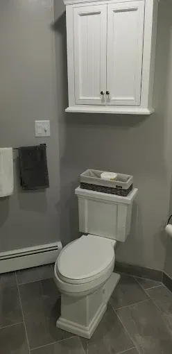 A bathroom with a toilet , sink , and cabinet.