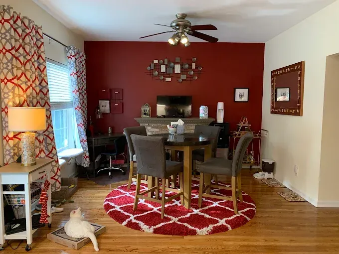 A living room with a red wall and a ceiling fan
