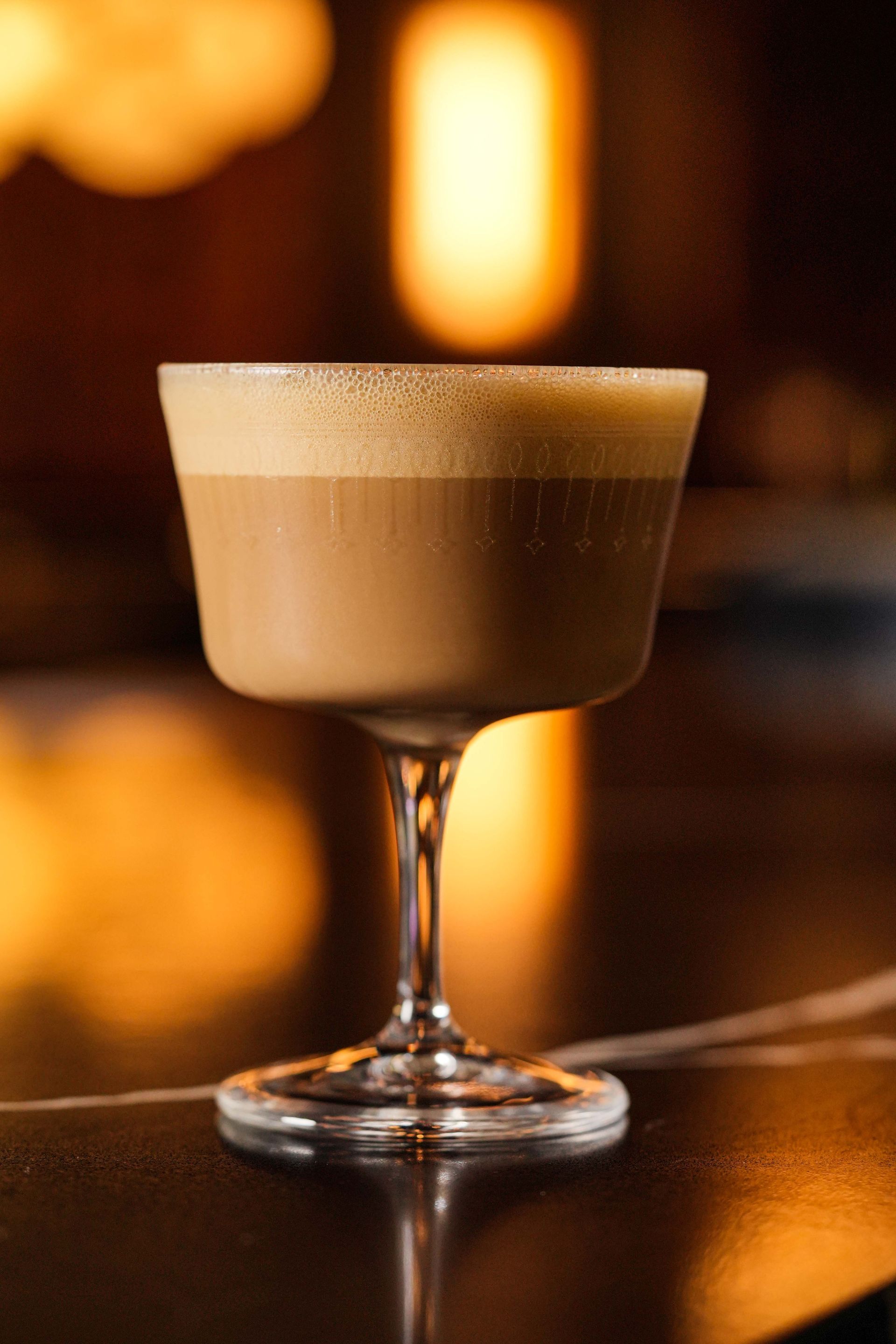 A close up of an espresso martini glass on a table.
