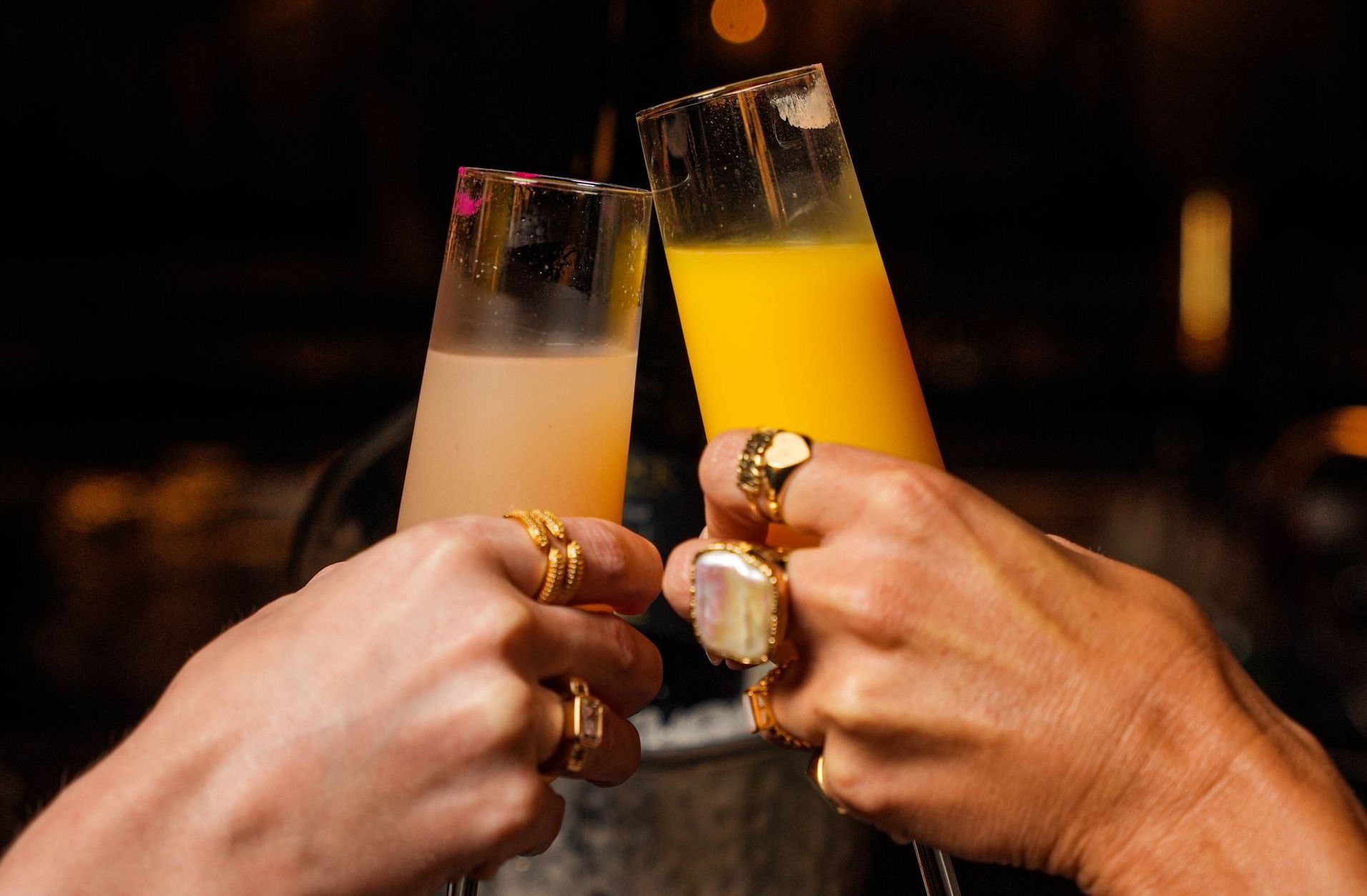 Two people are toasting with champagne glasses filled with orange juice.