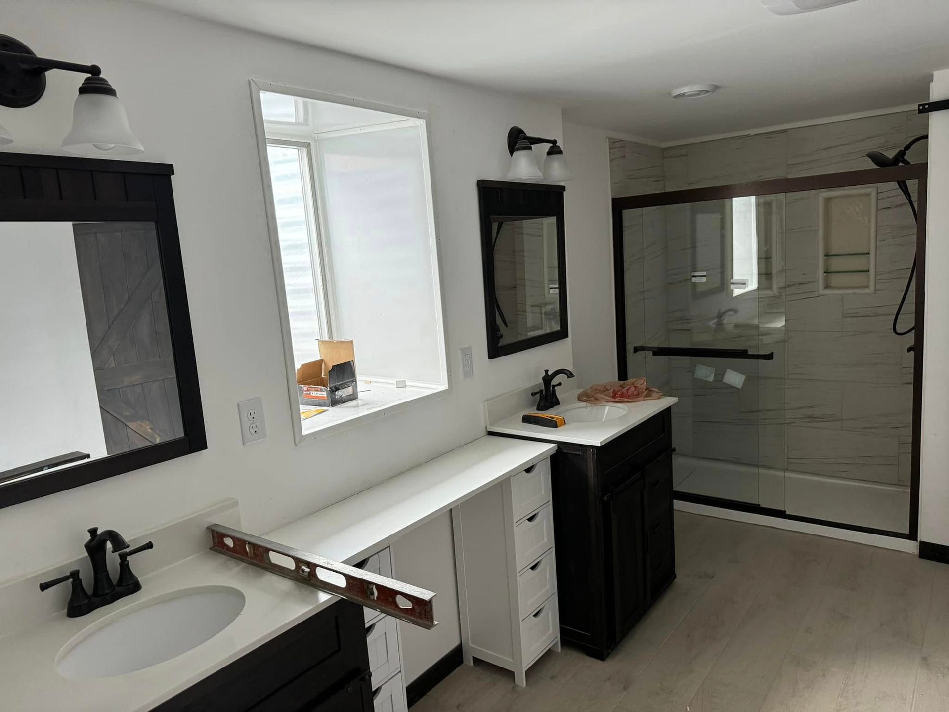 Bathroom remodel with two vanities, a long countertop, and a shower with a glass door.