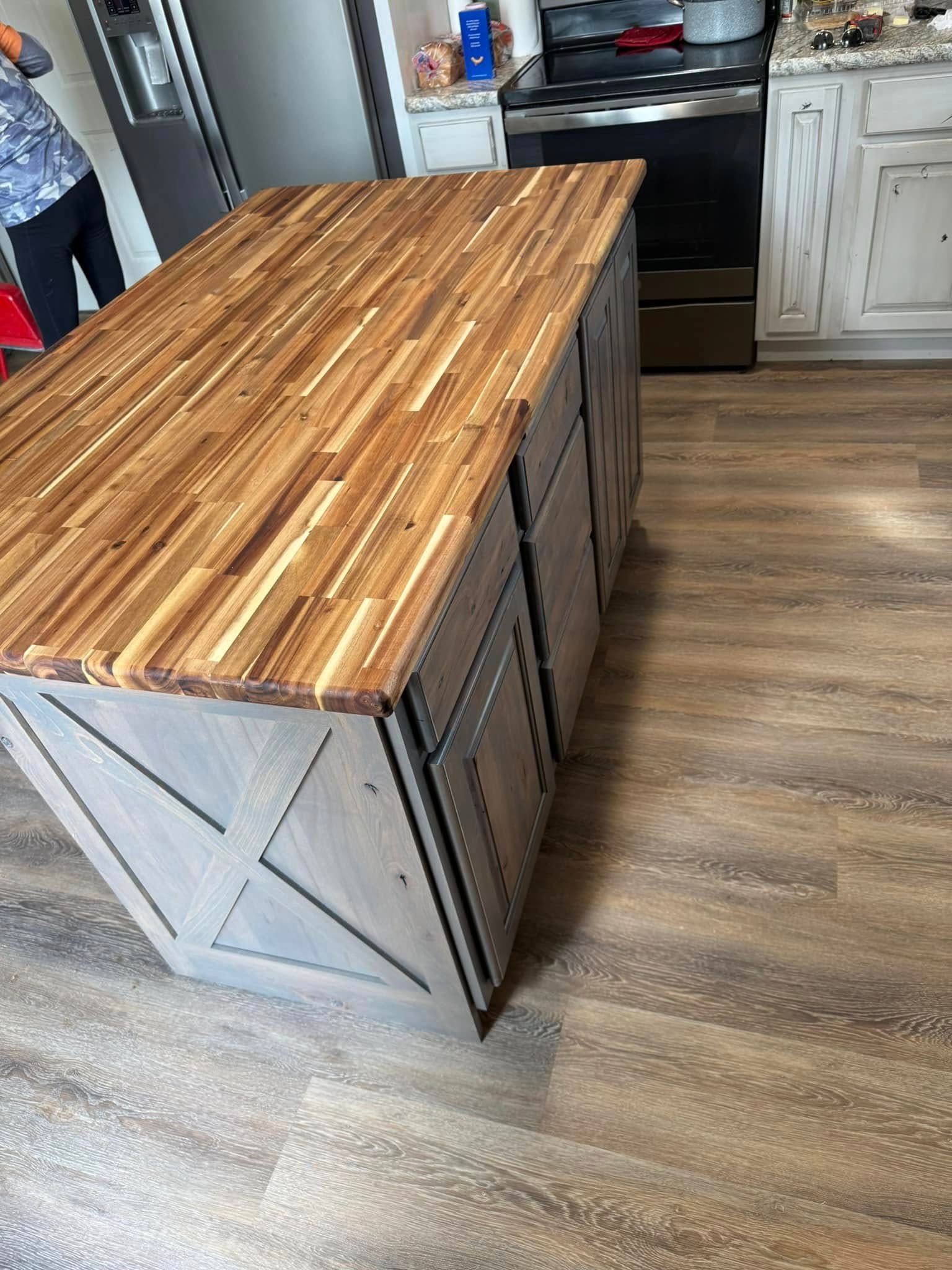 Kitchen island with wood butcher block top and gray cabinetry with X details.