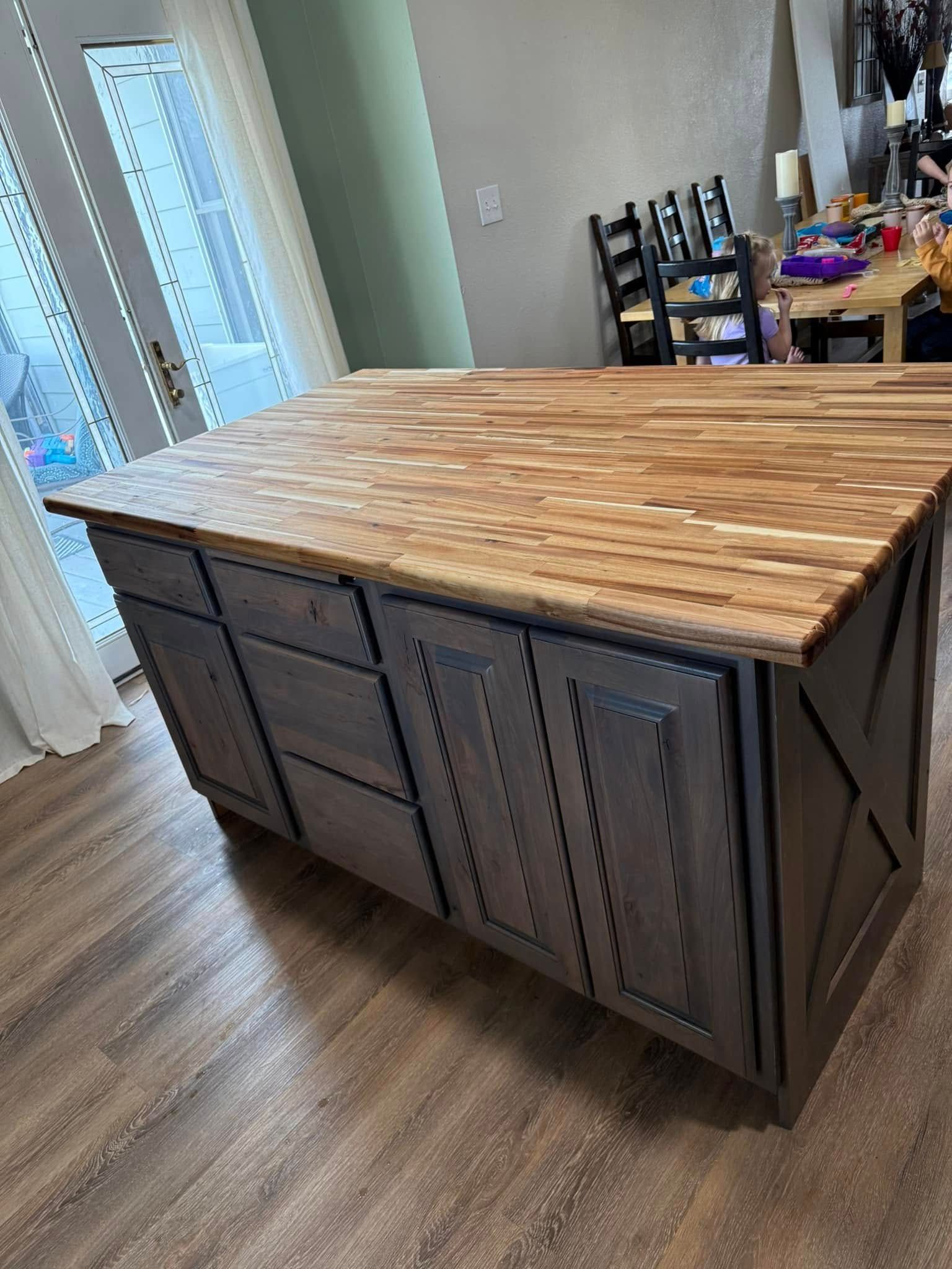 Wooden kitchen island with a butcher block countertop and gray cabinets.