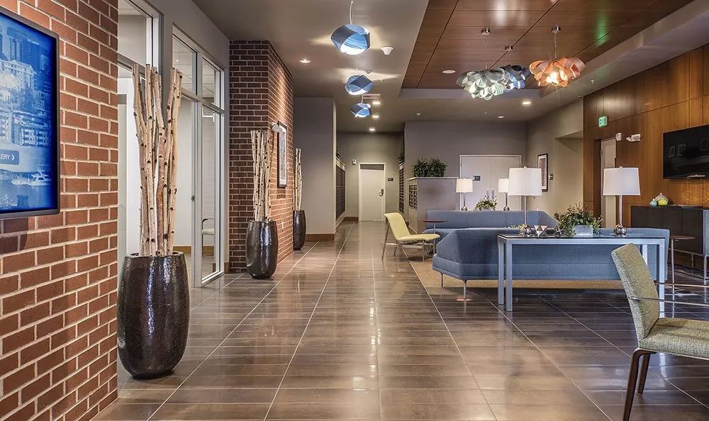 Hallway with brick wall, wood paneling, and seating area with a sofa and chairs.