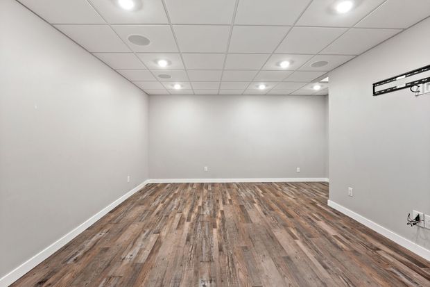 Empty modern room with gray walls, wood-look floor, and recessed ceiling lights