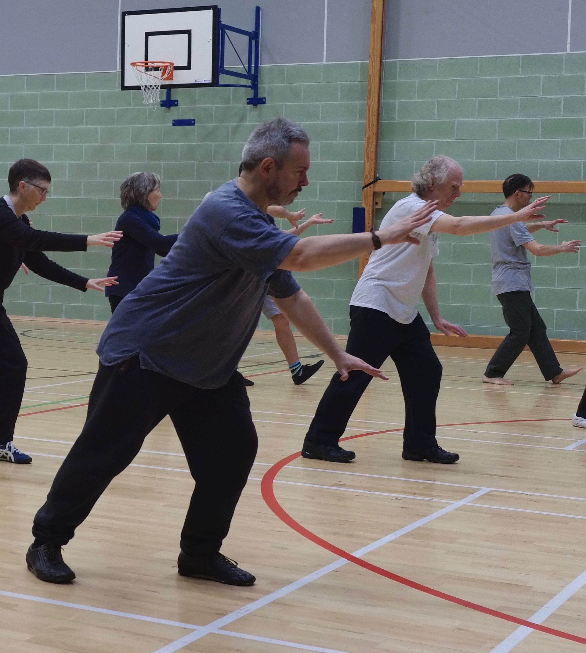 A group of people are practicing martial arts on a gym floor Tai Chi Chuan edinburgh