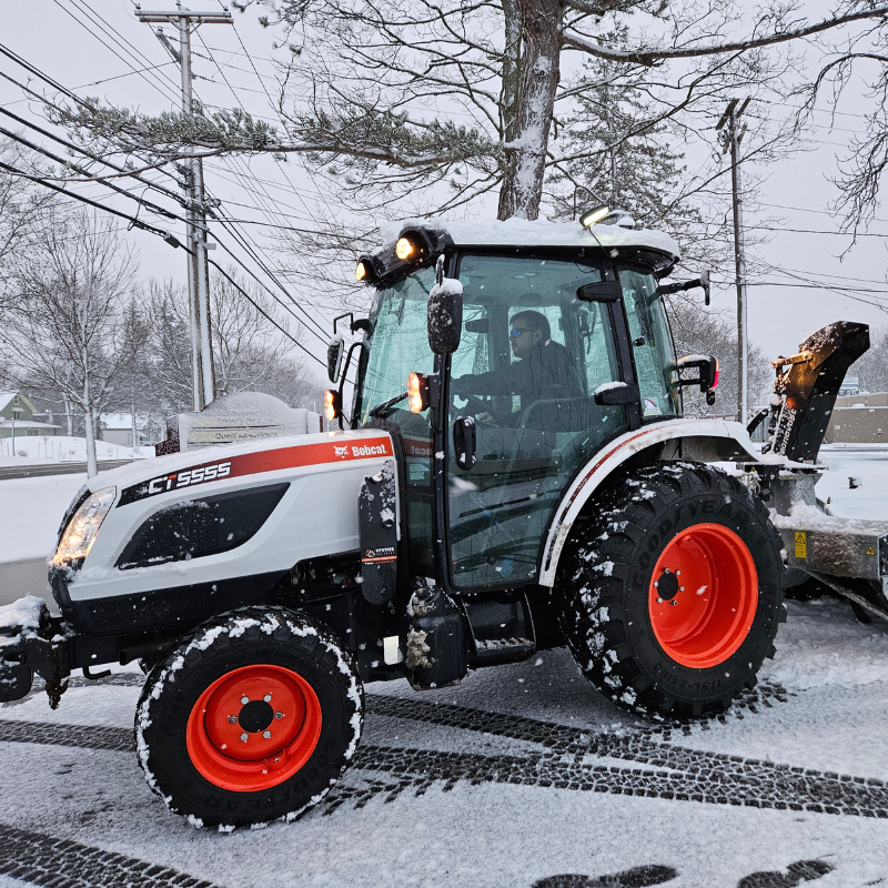 A bobcat tractor is parked in the snow