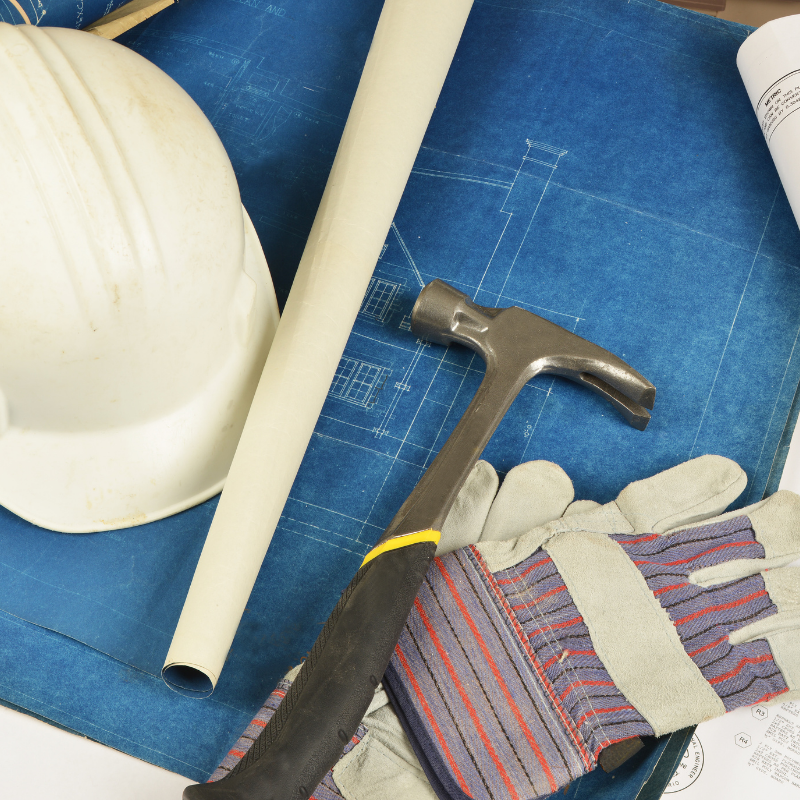 a hard hat hammer and gloves are on a blueprint