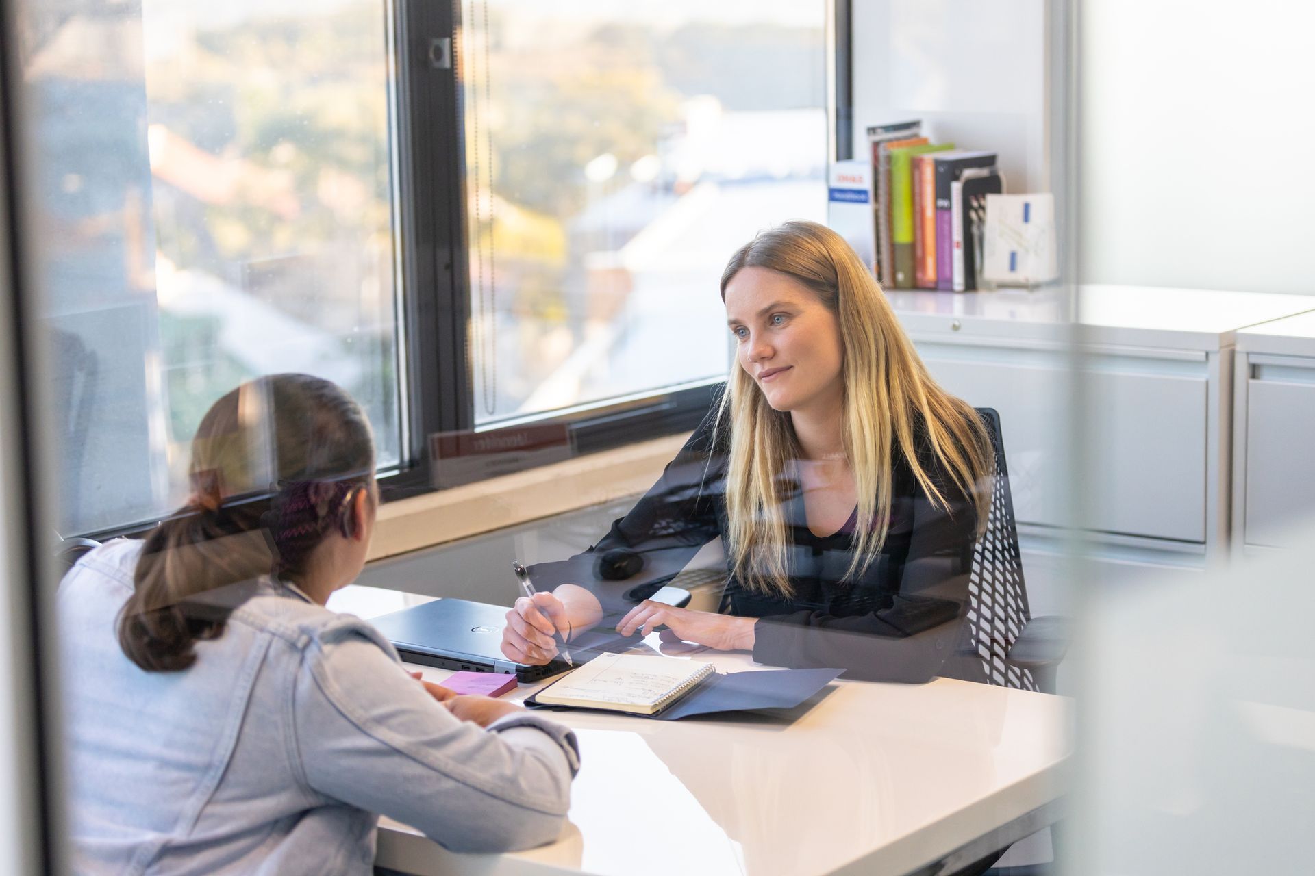 Two women are sitting at a table having a conversation.