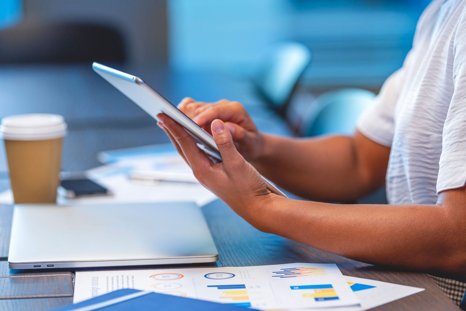 A person is sitting at a table using a tablet computer.