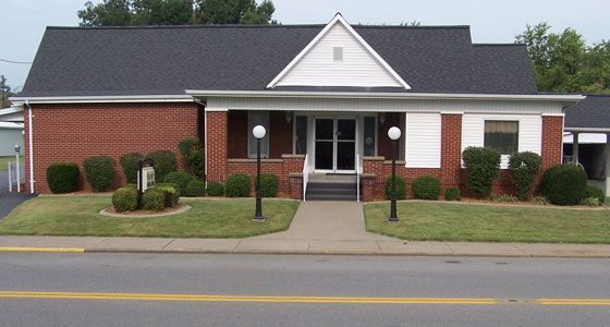 The front door of a house with a porch and plants in front of it.