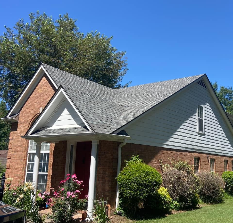 A brick house with a porch and a gray roof