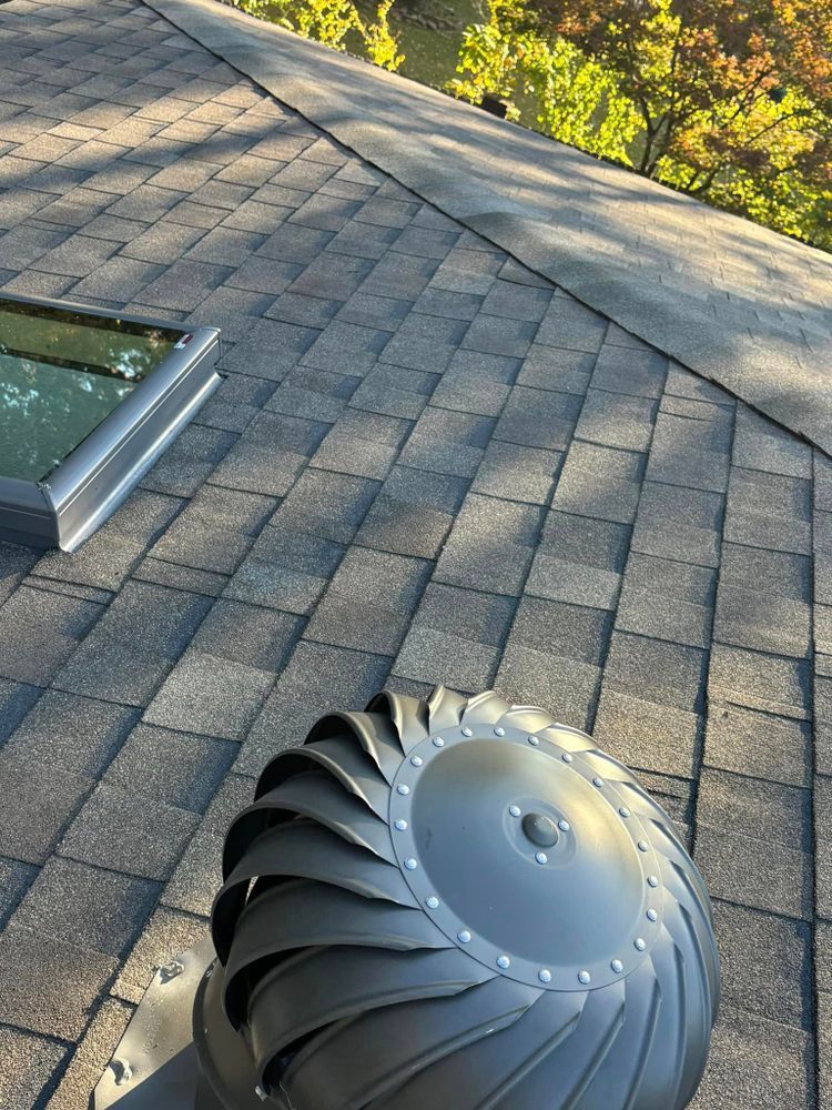A roof with a skylight and a fan on it.