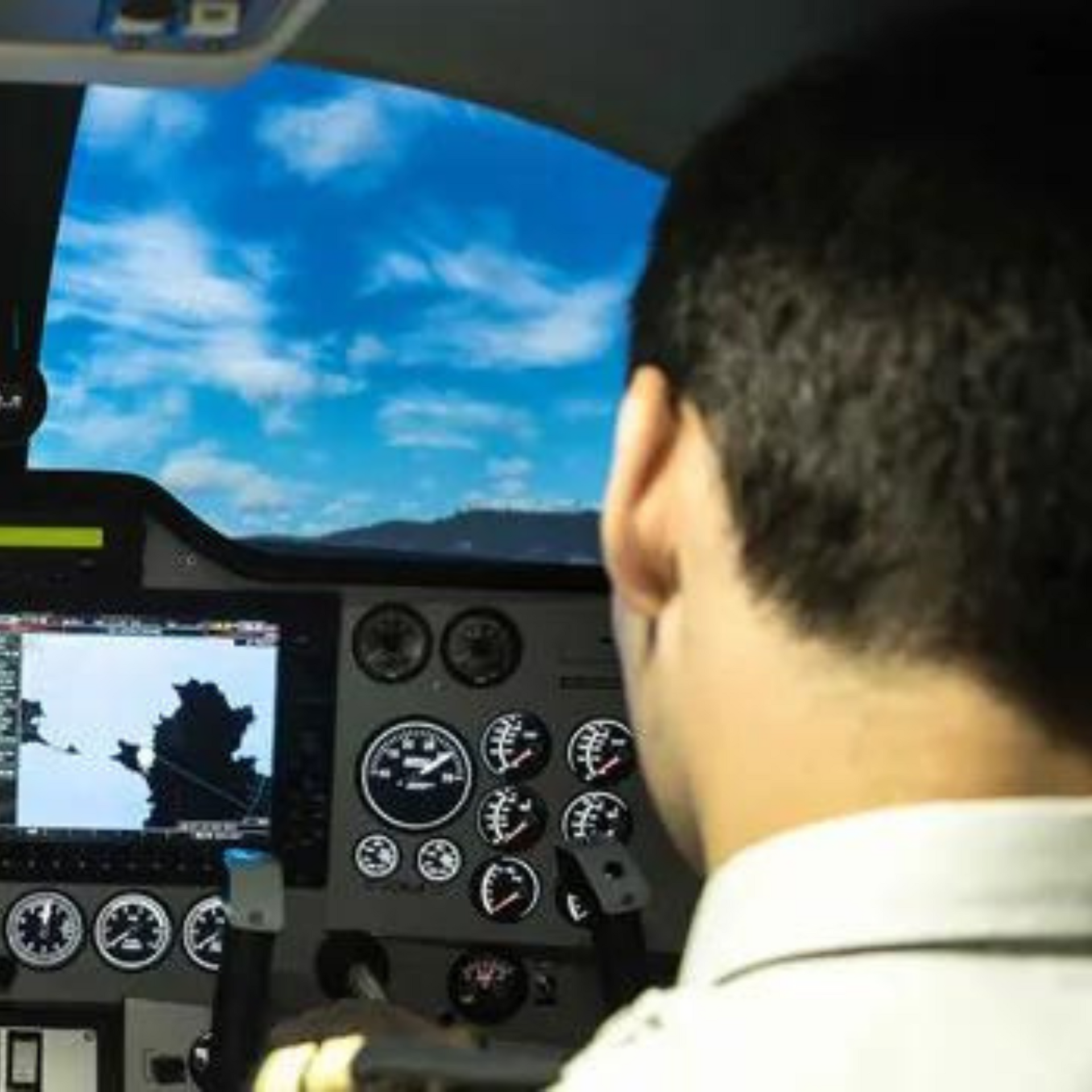 A man sitting in a cockpit looking at a monitor